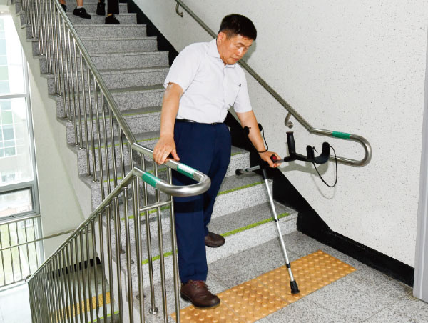 안전손잡이를 잡고 계단 아래 점자블록을
살피며 점검하는 김진철 심의위원