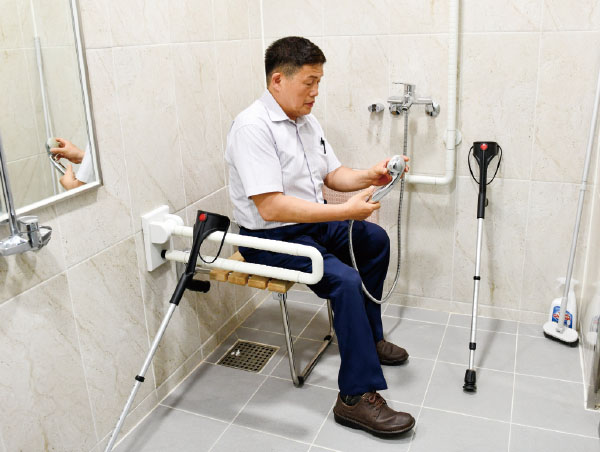 ‌의자와 안전 손잡이가 설치된 샤워 시설을 점검하는 김진철 심의위원